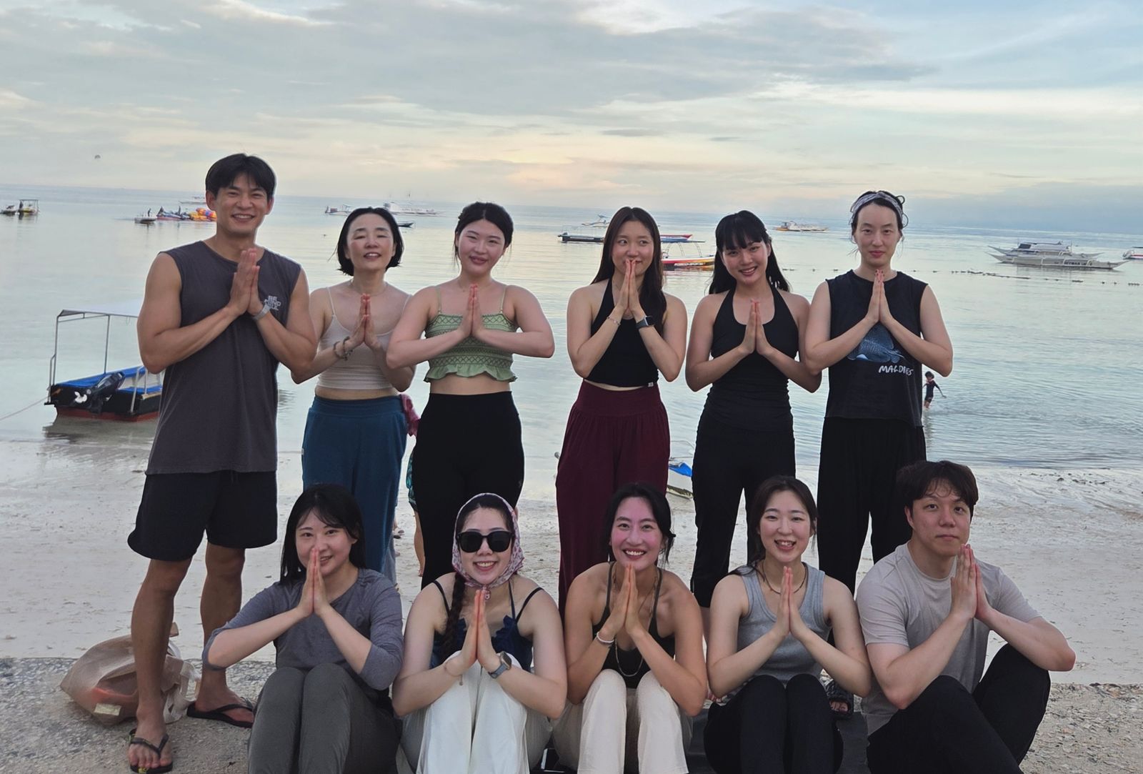 스티라 필리핀보홀 요가리트릿 — 보홀 바닷가에서 합장하고 단체 사진을 찍은 리트릿 참가자들